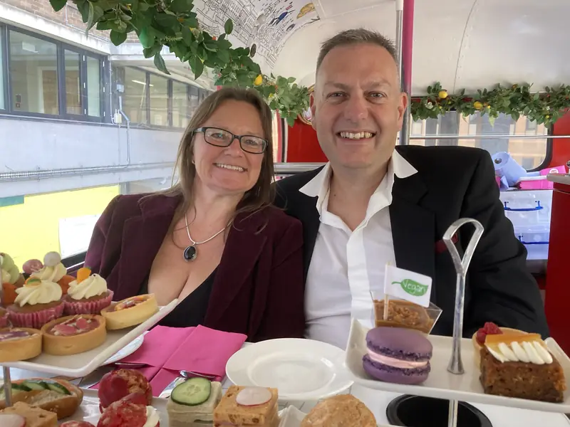 Philly and her husband enjoying afternoon tea on a vintage bus